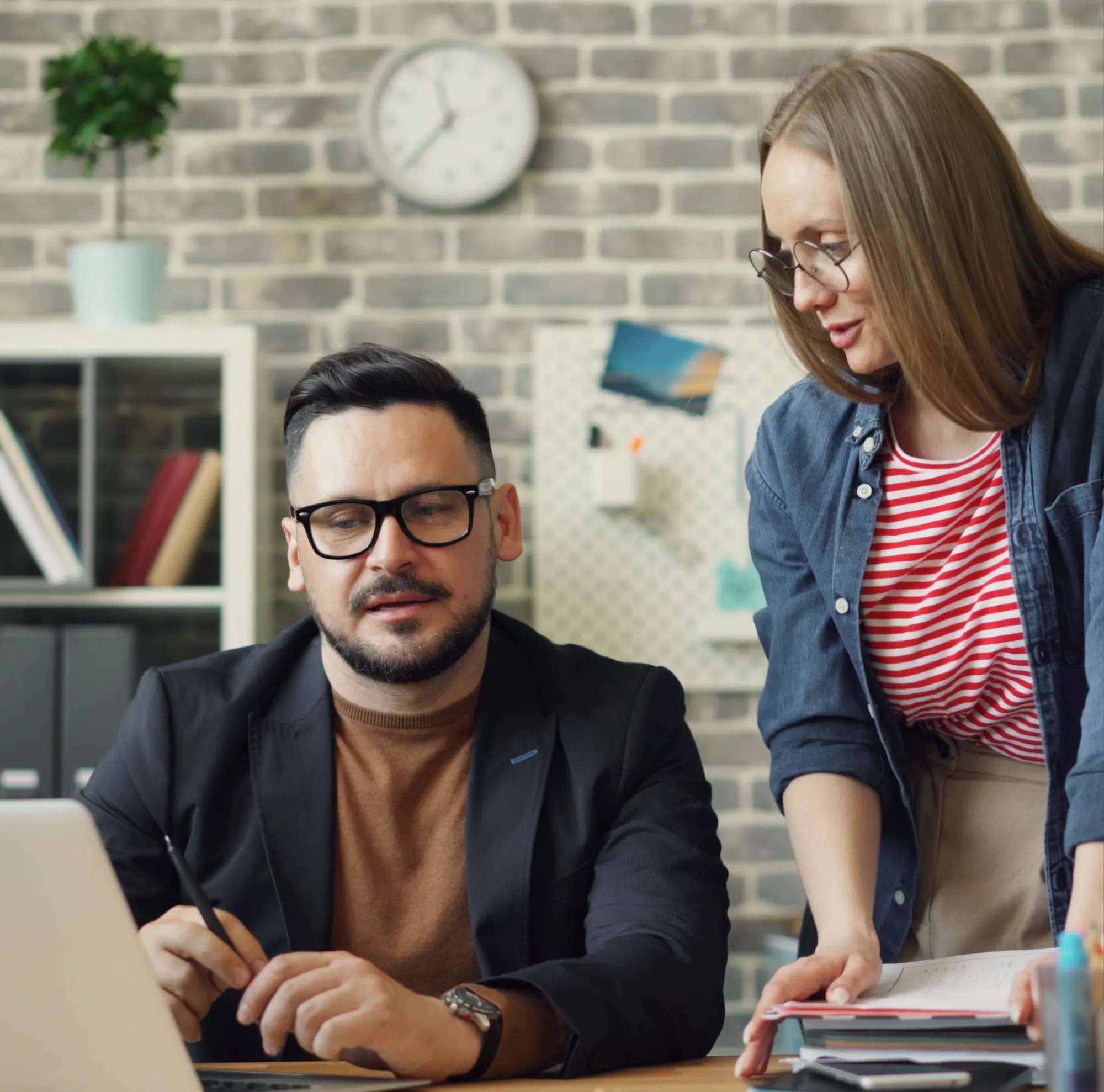 Two business partners discussing a project over a laptop at an office desk